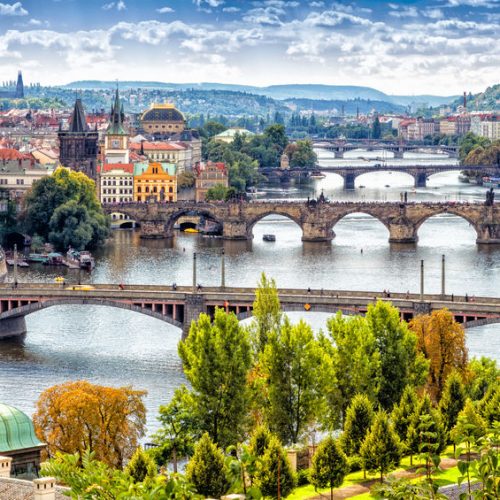 Scenic view of bridges on the Vltava river and of the historical center of Prague: buildings and landmarks of old town with red rooftops and multi-coloured walls.