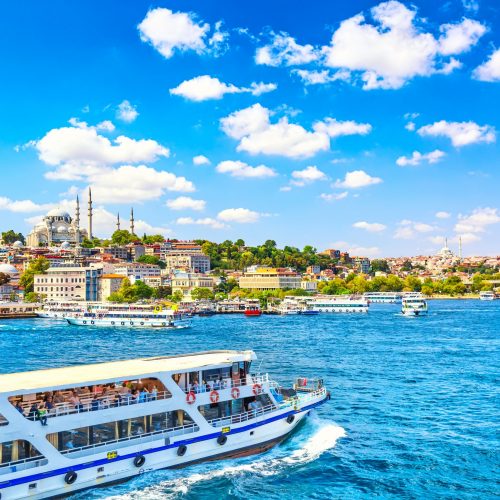 Touristic sightseeing ships in Golden Horn bay of Istanbul and view on Suleymaniye mosque with Sultanahmet district against blue sky and clouds. Istanbul, Turkey during sunny summer day